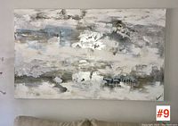 Straight-on view of the large abstract wall art painting hung above a beige couch, showing textured metallic silver and mixed colors.