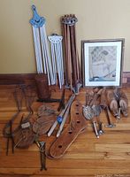 Full view of vintage bathroom and laundry accessories spread on floor including boot stretchers, shoehorns, pulleys, and framed print.