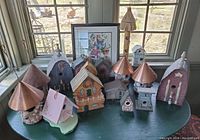 Full display of all decorative bird houses arranged on a table, visible colors and shapes.
