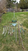 Photo showing full set of gardening tools arranged on grass with reel mower in the background