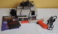 Front angle showing NES console, two controllers, light gun, instruction manuals and power adapter cables.