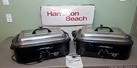 Two Hamilton Beach roaster ovens side by side with lids closed and box in background