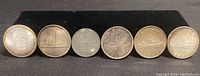 Full lot of six coins arranged in a row on black background