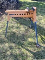 Full side view of the Triton Superjaws clamp horse showing orange body and four dark legs on grass outdoors.