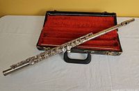 Silver tone flute outside of carrying case, showing full length and keys.