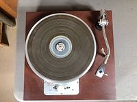 Top view of the vintage record player showing the wooden base and circular turntable with tonearm.