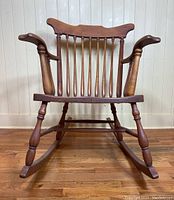 Front view of the antique wooden Boston rocking chair showing the spindle back, curved armrests, and turned legs.