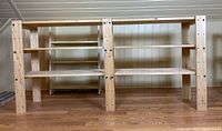 Front view of the wooden shelving unit showing three shelves with visible screws on the legs.