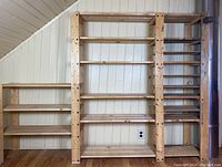 Full view of three connected pine shelving sections against wall