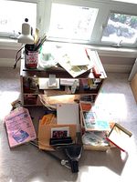 Wide view of laminate shelf on casters with various art papers, palettes, and small containers on and around it, near windows.