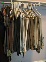 Photo of two hangers filled with men's belts and pants in size large, showing earth tone and neutral colors.