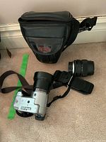 Sony 35mm camera body with attached lens, extra lens off to side, and black Optex camera case behind