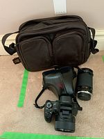 Overall lot including camera with leather case, extra telephoto lens, and black carry bag.