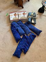 Photo showing four electric heating pads, three blue magic bags with red pattern, and two folded plain fabric magic bags tied with strings.