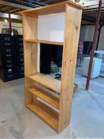 Front and side view of pine bookcase showing four shelves and partial open back.