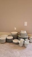Full view of Royal Cameo china collection including multiple stacks of plates, bowls, cups.