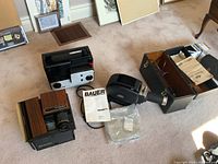 Overview of all projectors including Bauer T2 movie projector with manual and reel, E. Leitz Wetzlar slide projector with case, Bell and Howell slide projector.