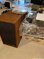 Pair of wood veneer speakers next to stacked packaging