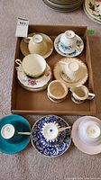 Overview of lot contents showing six teacup and saucer sets, cream pitcher and sugar pot