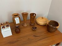 Wide view showing all 7 items on a wooden surface including lidded bowl, two sumac vases, 5 inch bowl, and two egg cups on their branded box.