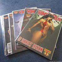 Five Vampirella comic books stacked showing front covers from dynamite entertainment with 'Scarlet Legion' subtitle.