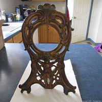 Full front view of the antique brass photo frame showing overall shape and ornate design including the cherub at bottom.