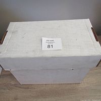Closed top view of a large white corrugated cardboard box containing comics, with a MaxSold label showing lot number 81