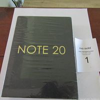 Front of the black box with gold lettering 'NOTE 20' in shrink wrap showing product packaging.
