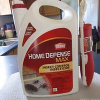 Front view of 5L white plastic container labeled Ortho Home Defense Max Insect Control Insecticide with attached battery-powered wand applicator.