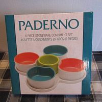 Box front showing the Paderno 6 piece stoneware condiment set with four colorful bowls and white tray.