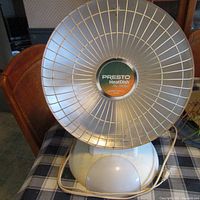 Front view of Presto HeatDish electric heater showing the metallic grill and the logo label in the center.