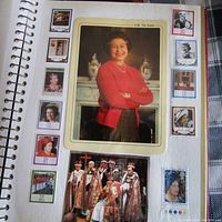 Page of scrap book featuring a large central photo of Queen Elizabeth II in a red sweater and various surrounding stamps depicting the Queen and royal imagery.