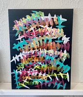 Front view of original abstract acrylic painting on black gallery canvas with multi-colored cross and curved brush strokes.