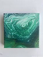 Image of small square canvas abstract painting with green fluid flow and white speckles.