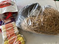 Plastic bag with beige and brown raffia ribbon, along with some other packaged craft materials.