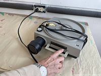 Side angle view of the Kodak slide projector showing power cord and lens.