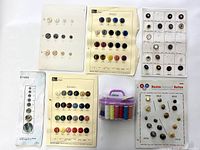 Overview photo showing five cards of vintage French buttons and one mini sewing kit with colorful thread spools in a purple case.