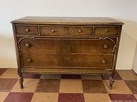 Front view of vintage wooden dresser showing all three smaller top drawers and two large bottom drawers with carved details.
