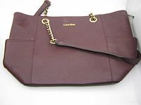 Front view of burgundy leather Calvin Klein handbag with gold-tone chain handles and visible wear on leather.