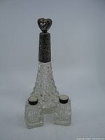 Full view of vintage crystal perfume bottle with ornate heart-shaped sterling silver stopper and pair of matching crystal salt and pepper shakers with silver tops.