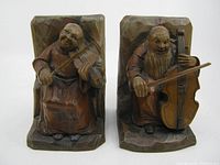 Front view of the pair of hand carved wooden monk musician bookends. One is playing violin, the other cello.