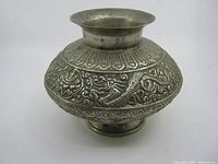Front view of the round metal vase showing dragon designs and flared rim
