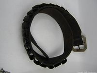 Full-length view of the rolled brown leather shotgun shell belt with metal buckle and cartridge holders.