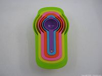 Top-down image of the nested plastic measuring cups and spoons showing all seven sizes and colors stacked together.