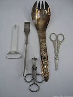 Photo showing five vintage metal kitchen tools arranged side by side on white surface.