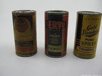 Front view of three vintage spice tins: Empire's Best Imitation Black Pepper, Servu Brand Turmeric, and Gold Standard Pure Spices Turmeric.