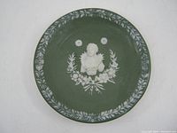 Full view of the green jasperware miniature plate with white relief decoration and border pattern.