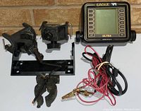 Fish finder with display, brackets, and cables arranged on white surface