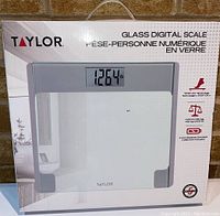 Front view of new Taylor glass digital scale in box showing model TY7566CAN with large LCD display.