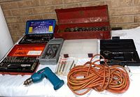 Mixed lot tools including socket sets, drill, and extension cord arranged on a surface